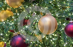 Yellow and burgundy matte Christmas balls on Christmas tree with a garland