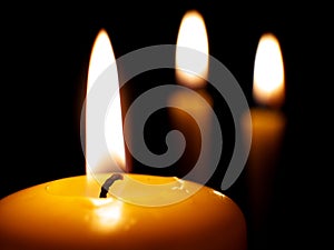 Yellow burning candles on dark background