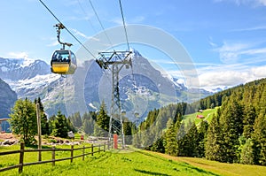 Yellow cable car in the Swiss Alps. Gondola going from Grindelwald to First in the Jungfrau area. Summer Alpine landscape with