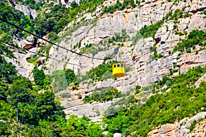 Yellow cable cars climbing Santa Maria de Montserrat abbey in Monistrol, Catalonia, Spain