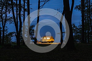 Yellow camper van parked in the forest at night. Camping in the wild nature