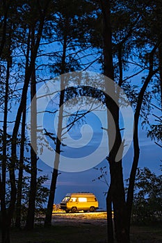 Yellow camper van parked in the forest at night. Camping in the wild nature