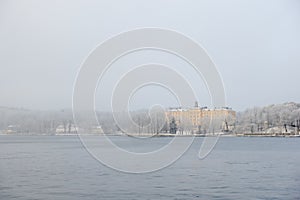Yellow Campus Manilla school building in snow covered Stockholm island of DjurgÃ¥rden in winter fog photo