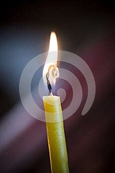 Yellow candle flickering against dark background