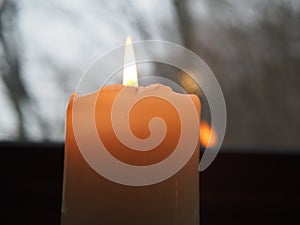 Yellow candle light in the dark and view by a window