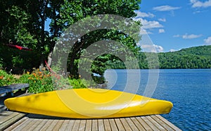 Yellow canoe on dock beside lake in summer time