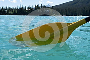 Yellow canoe paddle in the teal water of Emerald Lake in Yoho National Park Canada