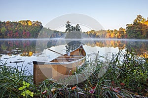 Yellow canoe on shore of calm lake with island and trees in fall color in northern Minnesota