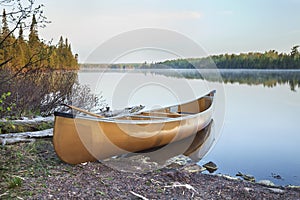 Yellow canoe on shore of northern Minnesota lake in early morning light