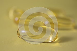 Yellow capsule on a light background. Vitamin D keeps you healthy in the absence of the sun.