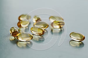 Yellow capsule with vitamin E tocopherol on blue surface