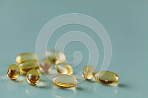 Yellow capsule with vitamin E tocopherol on blue surface