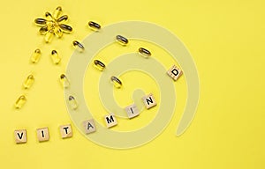 Yellow capsules in the form of the sun with rays and word vitamin D from wooden cubes with letters