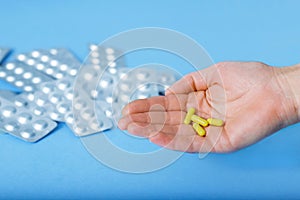 Yellow capsules on the palm of the hand and different blister of pills. Different pills. Medical and different concept