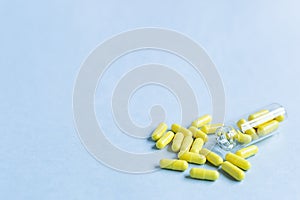 Yellow capsules are poured out of a bottle on a blue background. Omega-3 vitamins. food Supplement. Fish oil in capsules