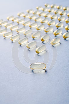 Yellow capsules with vitamin D on a blue background. Sunshine vitamin