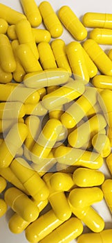 Yellow capsules on white background. Selective focus.