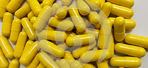 Yellow capsules on white background. Selective focus.
