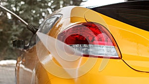 Yellow car back washed at self serve carwash, jet water stream s