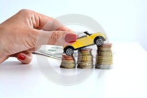 Yellow car climbing on pile of coins suggesting increase of sales trend