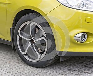 Yellow car closeup - front wheel with light alloy rim