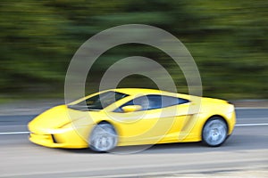 Yellow car driving fast on country road