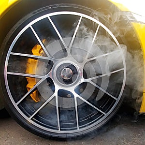 Yellow car with light alloy wheels with carbon ceramic brakes and smoke from it. Close up, square image