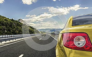 Yellow car rushing along a high-speed highway.