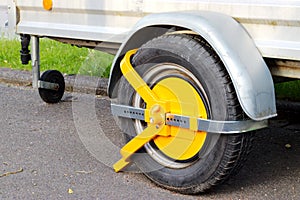 Yellow car wheel lock on a car trailer