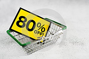 Yellow card mini grocery shopping basket with eighty percent discount sign. Conceptual image of a clearance sale, season