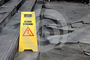 Yellow caution cleaning progress sign on the floor outdoors