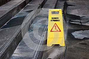 Yellow caution cleaning progress sign on the floor outdoors