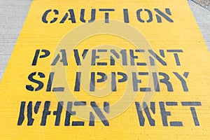 Yellow Caution Pavement Slippery When Wet Sign on the Ground