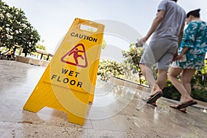 Yellow caution sign and blur of paeple walking on the walkway