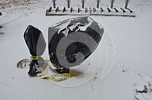 Yellow caution tape and black plastic bag on water fountain with snow
