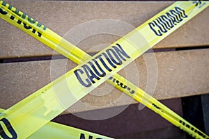 Yellow caution tape in english and spanish barring access to park bench at a park due to quarantine from COVID-19 photo