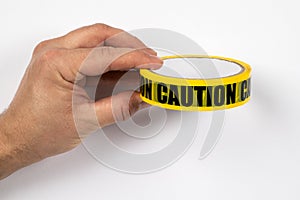 Yellow CAUTION tape in a man& x27;s hand on a white background