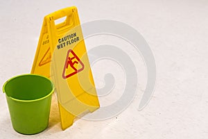 Yellow caution wet floor sign on broken mall floor tiles