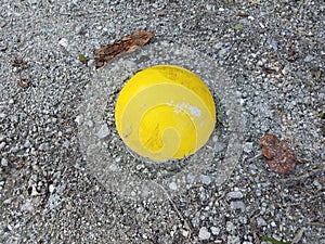 Yellow cement sphere in ground with pebbles