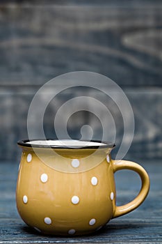 Yellow Ceramic Mug with White Dots on Blue Wooden Background