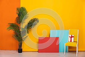 yellow chair with gift with green plant on yellow as background red blue