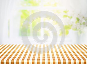 Yellow checkered tablecloth texture top view with abstract green garden from window background