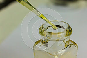 Yellow chemical transparent liquid in pipette tip dropping to cl