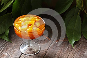 Yellow cherry jam with lemon and vanilla in a glass bowl on a wooden background.