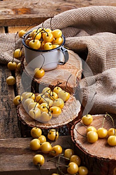 Yellow cherry in a rustic style on a wooden background. Berries of ripe fresh cherries in a cup.