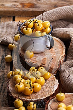 Yellow cherry in a rustic style on a wooden background. Berries of ripe fresh cherries in a cup.