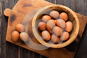 Yellow chicken eggs in a wooden bowl on a wooden background