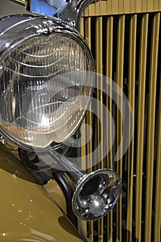 Yellow classic car headlight, horn, and partial grill