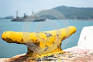 Yellow cleat on naval port with navy ship going to the harbour