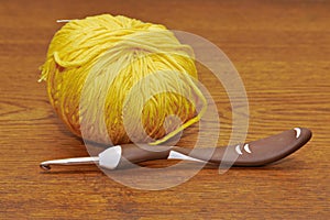 A yellow clew with a crochet hook on the table